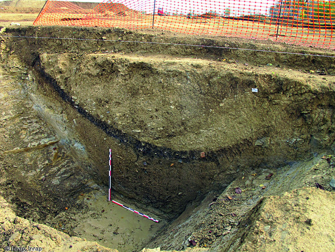 Coupe du fossé de l'enclos principal de l'établissement protohistorique des Grands Champs à Coulon (Deux-Sèvres), fin du IIe-Ier s. avant notre ère, 2011.Trois séquences de comblement sont ici lisibles : la fine couche au centre, un dépotoir, est scellée par un important remblai issu du démantèlement du talus.    Photo publiée dans le numéro 35 de la revue de l'Inrap <a class= rte-link-ext  href= http://www.inrap.fr/archeologie-preventive/Recherche-scientifique/Archeopages/Les-numeros/HS03-34-35-2012/Numero-35/Actualite/p-17153-Esp