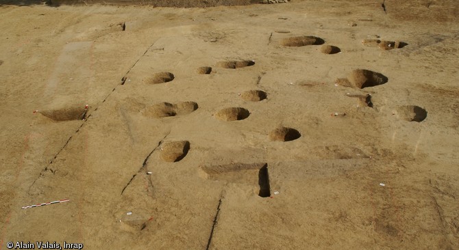 Vue générale du bâtiment des XIIIe-XIVe s. découvert à Juigné-sur-Sarthe (Sarthe), 2012.Les trous de poteaux dessinent au sol le plan d'un édifice en bois d'une superficie de 100 m2. Les poteaux présentent un diamètre de 0,5 m. La construction mesurait 10 m de côté. 