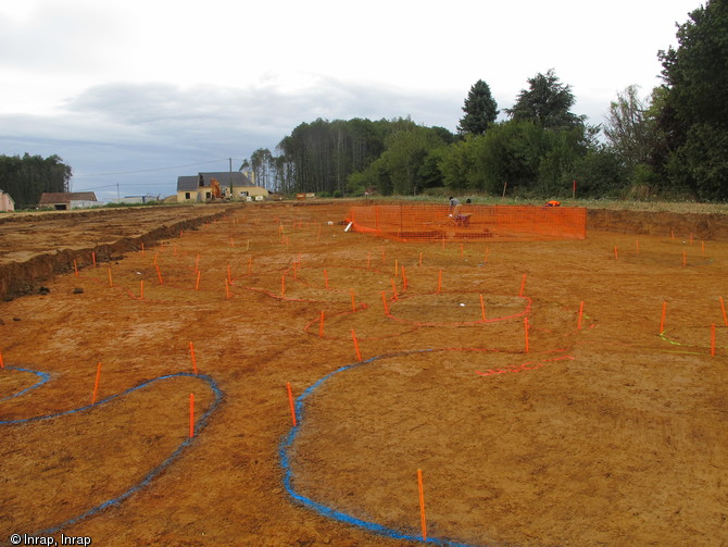 Vue du site du Bois Beslan depuis le nord-ouest, La Milesse (Sarthe), 2012.La surface de la mine a été décapée à l'aide de pelles mécaniques. Les puits et les effondrements, reconnaissables au changement de couleur de la terre, sont marqués à la peinture et avec des jalons pour aider au relevé topographique.