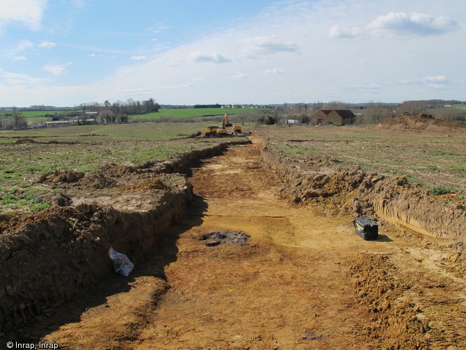 Début de l'opération archéologique menée à la Mare sur la commune de La Milesse (Sarthe), 2012.Dans la tranchée apparaît au premier plan un four métallurgique isolé. Au dernier plan, là où la pelle mécanique travaille, un second atelier est mis au jour.