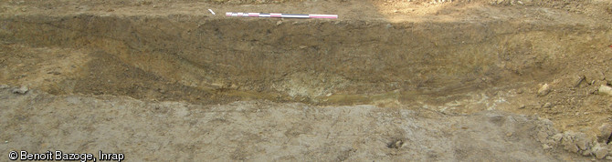Vue en coupe d'un chemin creux repéré sur le site des Chauvières à La Quinte (Sarthe), 2012.La fouille a mis en évidence un habitat rural occupé entre les Xe et XIVe s., situé à 400 m de l'ancienne voie romaine reliant Le Mans à Jublains.