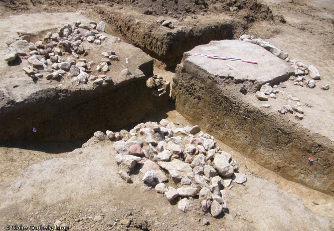 Bâtiment sur solin de pierre des XIIe-XIIIe s. en cours de fouille, La Quinte (Sarthe), 2012.Au tournant du XIIe et du XIIIe s., le carrefour de voies à proximité du site des Chauvrières se décale d'une centaine de mètres vers l'ouest. La portion abandonnée d'un chemin creux a alors été investie par les occupants du lieu et deux bâtiments y ont été construits.