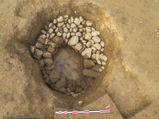 Aménagement d'un puits antique dont les pierres de la partie supérieure ont été récupérées après l’abandon du sanctuaire mis au jour à La Grillère, Saint-Denis-du-Maine (Mayenne), 2012.Le comblement très humide a permis la conservation de bois antique.