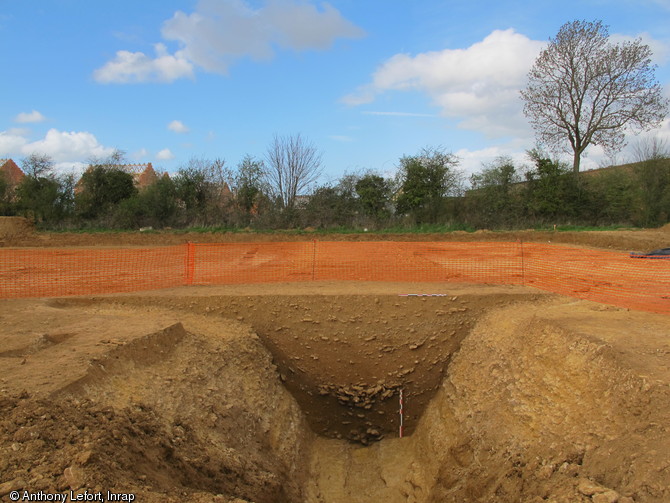 Vue en coupe du fossé de l'enclos monumental au niveau de l'entrée de la place forte gauloise de Bourguébus (Calvados), 2013.De puissants fossés délimitent la place forte. Les plus importants atteignent 4 m de profondeur pour plus de 6 m de large. Ces ouvrages sont d’autant plus impressionnants qu’ils ont été creusés dans la roche sur plusieurs centaines de mètres de longueur. 