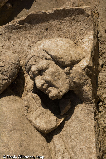  Vue de détail du visage de la vieille servante chuchotant la cachette de Vénus, IIe s. de notre ère, bas-reliefs de la façade monumentale du sanctuaire gallo-romain de Pont-Sainte-Maxence (Oise), 2014.    