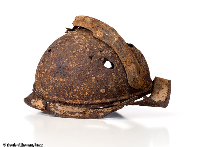 Casque d'infanterie français de 1915 dit  casque Adrian . L'insigne monté sur le devant du casque ayant disparu, on ne peut pas déterminer l'appartenance à une arme ou à un régiment. Ce casque est constitué de quatre pièces principales, la bombe, la visière, le cimier et la nuquière. Découvert fortuitement par un employé du BTP à Givet (Ardennes), 2003