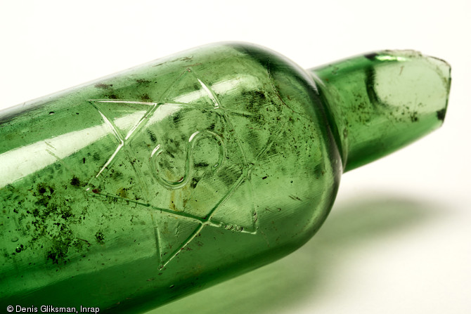 Bouteille de bière française marquée de l'étoile des brasseurs, vers 1917, découverte à Marcilly-sur-Tille (Côte-d'or), 2011.  L'étoile des brasseurs est une représentation symbolique de l'alchimie brassicole mettant en oeuvre les quatre éléments (terre, feu, eau, air).