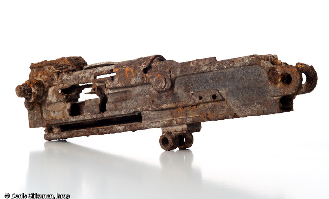 Mitrailleuse française de la marque Hotchkiss en acier usiné,  de calibre 8mm Lebel, découverte dans une tranchée de la Grande Guerre à Amiens (Somme), 2011.  Cette mitrailleuse pouvait être alimentée de deux sortes de bandes (rigide à 24 cartouches ou articulée à 251 cartouches), et était utilisée en casemate ou sur véhicule léger sur un affût-trépied, également découvert sur place. 45850 exemplaires ont été produits de 1914 à 1918. Elle sera également en usage durant la Seconde Guerre mondiale, puis dans une moindre mesure en Indochine et en Algérie. 