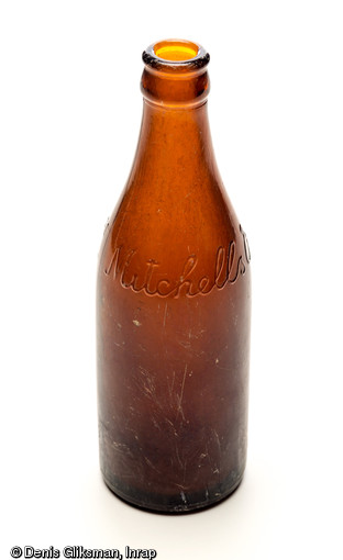 Bouteille de bière portant la marque  Mitchells & Butler Ltd , brasserie anglaise fondée au XIXe siècle à Smethwick dans les Midlands, datant de la Bataille de Normandie (été 1944) et découvert dans le comblement d'un trou de bombe au château de Caen (Calvados), 2011.