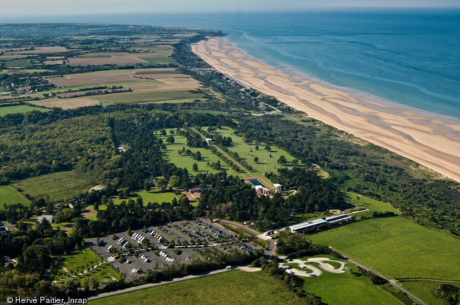 Vue aérienne d'Omaha Beach, ici entre Colleville-sur-Mer et Saint-Laurent-sur-Mer (Calvados), l'une des cinq plages du débarquement de Normandie. Les troupes américaines y débarquèrent au matin du 6 juin 1944 et y subirent les plus lourdes pertes (4000 morts), en raison d'une mer agitée qui enpêcha la sortie des blindés, un secteur difficile d'accès, et une forte résistance allemande. Elle reçu le nom de code Omaha (ville du Nebraska) par les Américains et le surnom de  Bloody Omaha  (Omaha la sanglante).