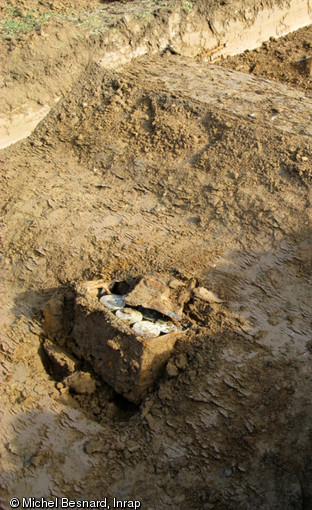 Caisse de munition datant de la Bataille de Normandie et découverte lors de sondages archéologiques à Grentheville (Calvados), 1992.  Le godet de la pelle mécanique utilisée pour décaper la terre végétale a été relevé et la caisse laissée en place dans l'attente des démineurs.