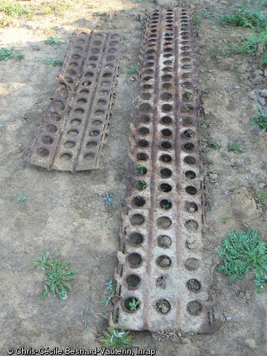 Vestiges de plaques métalliques ajourées de type PSP  Pierced Steel Planks  mises au jour à Bretteville-l'Orgueilleuse (Calvados), 2011.  Ce type de plaques servait comme aide au franchissement pour les véhicules et comme pistes aériennes sommaires mises en place par les sapeurs du Génie en moins de vingt-quatre-heures. Elles dépendaient de l'aérodrome de Coulombs, aménagé par la RAF du 16 juin au 30 août 1944, lors de la Bataille de Normandie.