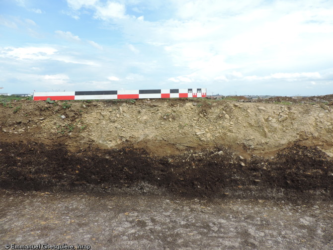 Vue partielle du tertre  du monument funéraire 29 construit en mottes de gazon surmonté ici de la couche calcaire du chemin antique. Nécropole du Néolithique moyen à Fleury-sur-Orne (Calvados), 2014.  
