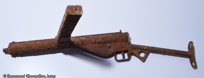 Pistolet mitrailleur type  Sten Mark III , calibre 9mm, de fabrication britannique, version simplifiée du modèle Mark II qui équipa principalement les chefs de section. Cette arme fut largement distribuée aux troupes britanniques et canadiennes pendant la Bataille de Normandie. Découvert sur le site d'un camp canadien occupé du 25 juillet au 5 août 1944, en cours de fouille à Fleury-sur-Orne (Calvados).