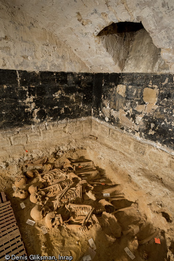 Alignement de squelettes d'une fosse commune comprenant plus de 150 individus, mise au jour dans la cave d'un supermarché à Paris, en 2015.  Ce supermarché occupe l'ancien immeuble Félix Potin, construit à l'emplacement du cimetière de l'hôpital de la Trinité, fondé au XIIe siècle et détruit à la fin du XVIIIe siècle. Neuf sépultures ont été découvertes. 