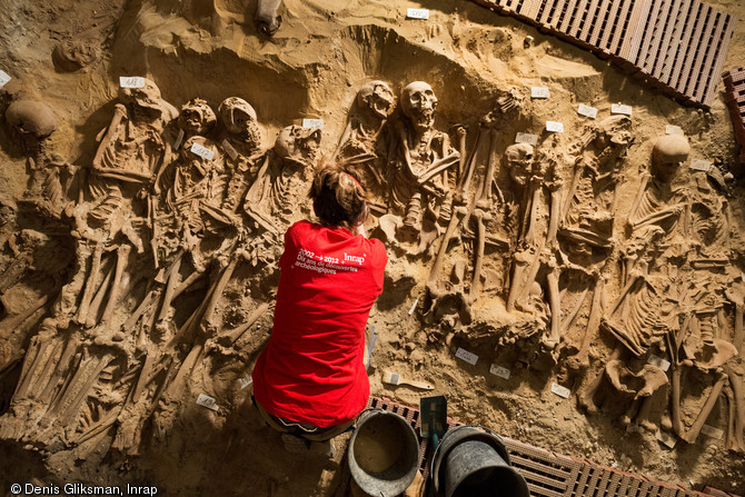 Vue zénithale d'une grande fosse commune comprenant comprenant plus de 150 individus, mise au jour dans la cave d'un supermarché à Paris, en 2015.  Ce supermarché occupe l'ancien immeuble Félix Potin, construit à l'emplacement du cimetière de l'hôpital de la Trinité, fondé au XIIe siècle et détruit à la fin du XVIIIe siècle. Neuf sépultures ont été découvertes. 