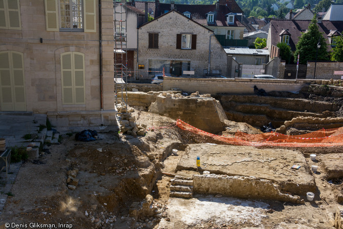 Vue générale des fouilles : au premier plan, les restes du manoir seigneurial des XIIIe-XIVe siècles et à l'arrière-plan, le glacis de la tour d'angle du château, renforcée dans la seconde moitié du XIVe siècle à Viarmes (Val-d'Oise), 2013.